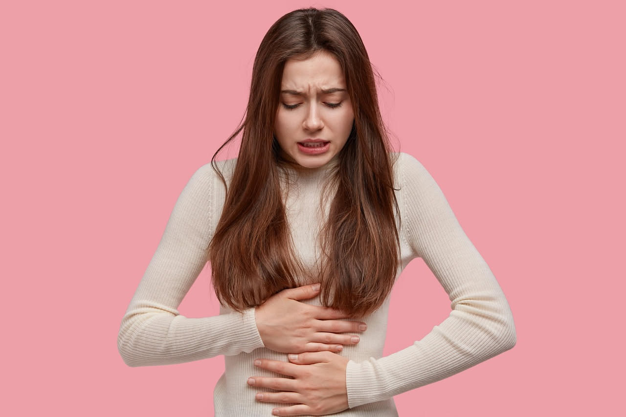 Illustrazione anatomica dell'intestino crasso e tenue con frecce che indicano il movimento peristaltico, su sfondo chiaro con tonalità azzurre e grigie