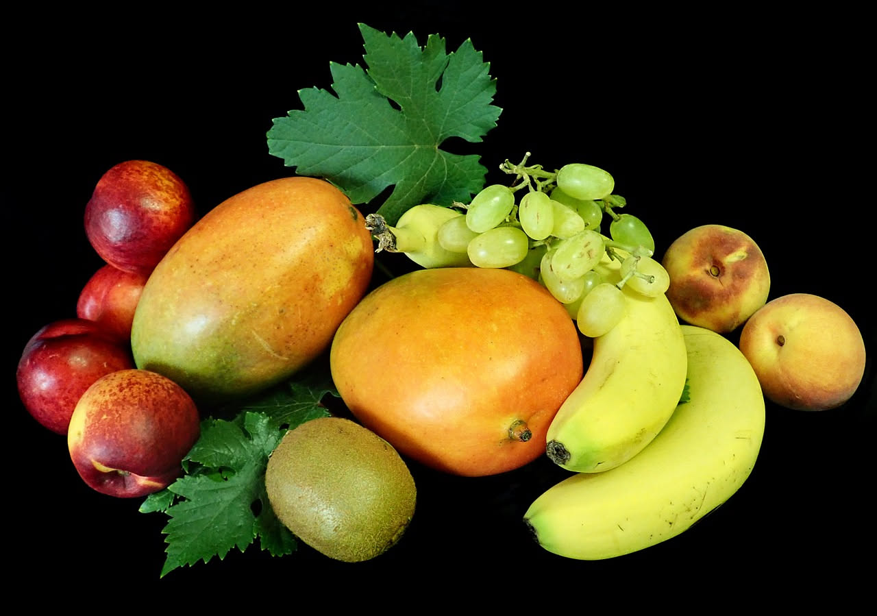 Tavolo con meloni, fragole, pesche e ciliegie fresche d'estate, sole splendente, frutta tagliata in pezzi colorati su piatto bianco