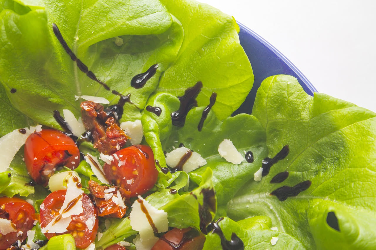 Insalata mista con lattuga croccante, pomodori rossi, cetrioli verdi e verdure colorate in una ciotola di vetro con gocce d'acqua fresca