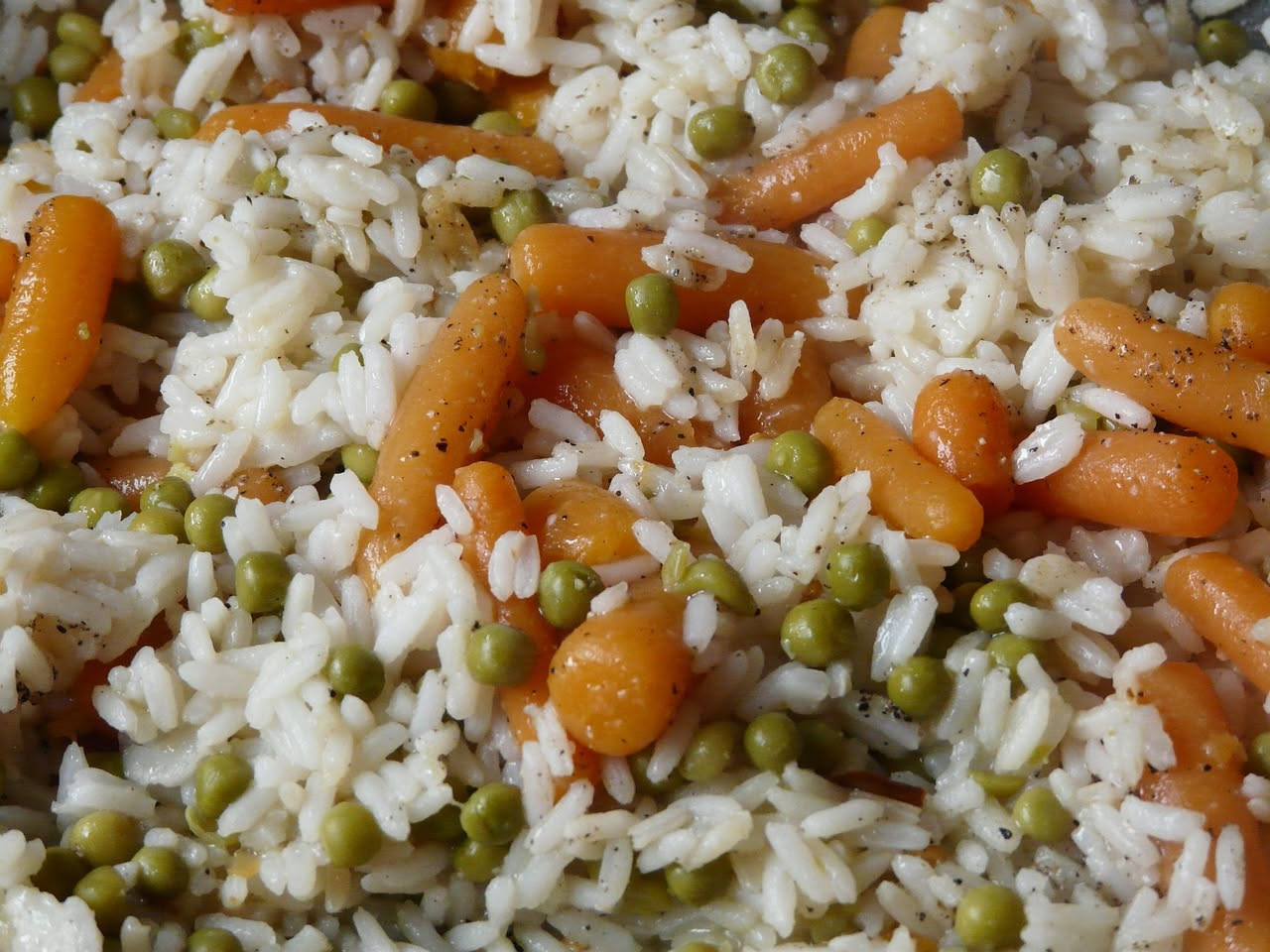 Ciotola di insalata di riso fresca con verdure colorate, pomodori, cetrioli, mais e condimento a base di olio, su tavolo di legno naturale